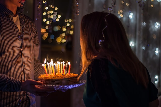 Dziewczyna zdmuchuje świeczki z tortu urodzinowego