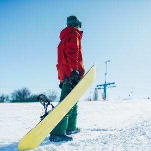 mężczyzna z deską snowboardową na stoku
