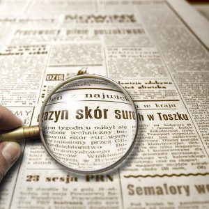 Lupa powiększająca tekst w starej gazecie, symbolizująca dokładne sprawdzanie informacji