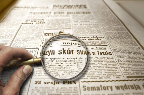 Lupa powiększająca tekst w starej gazecie, symbolizująca dokładne sprawdzanie informacji