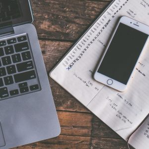 Laptop, smartfon i notes z zapisanym planem na drewnianym biurku